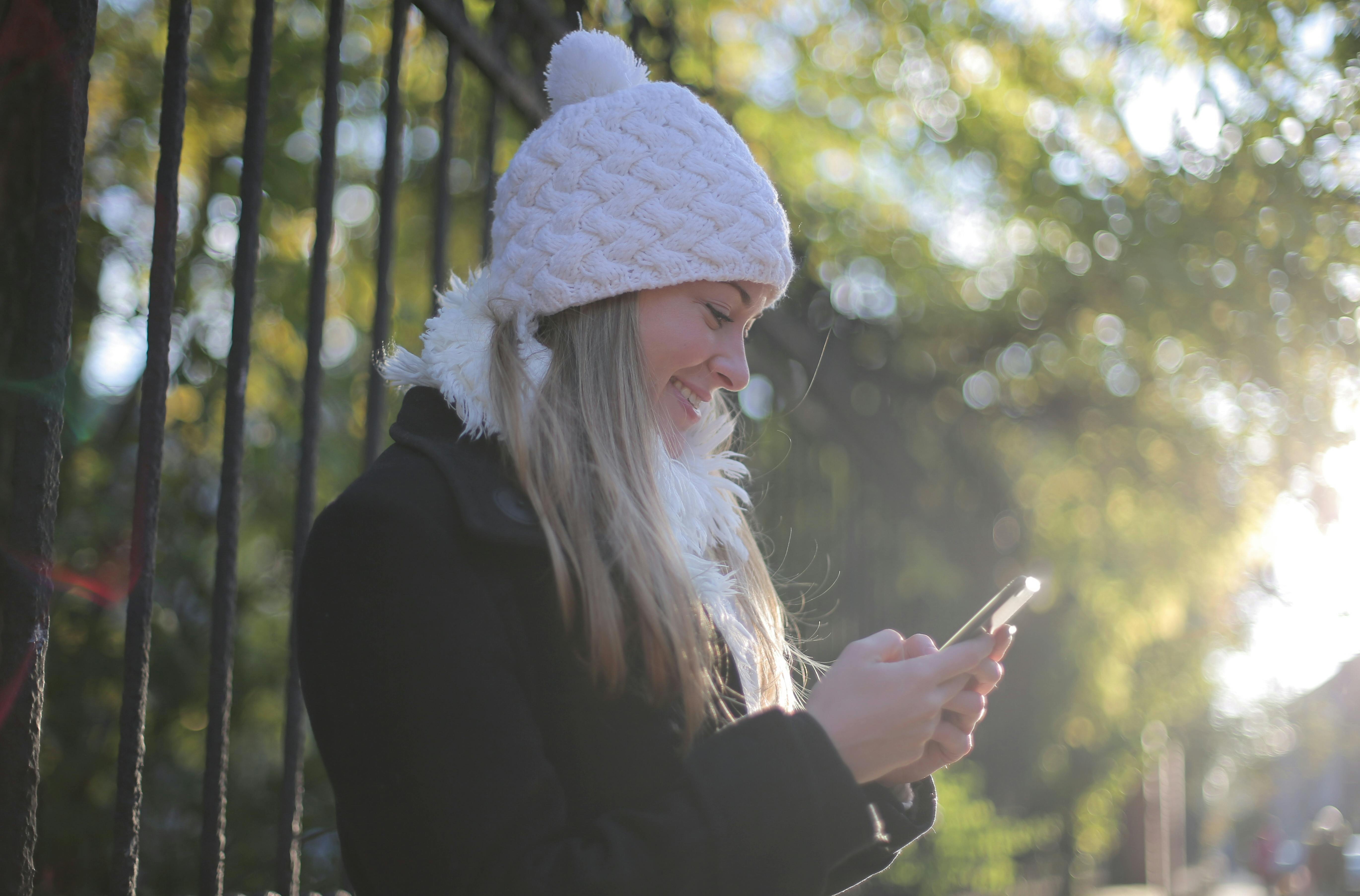 Woman smiling while using a smartphone to navigate financial guidance on The Cash Navigator